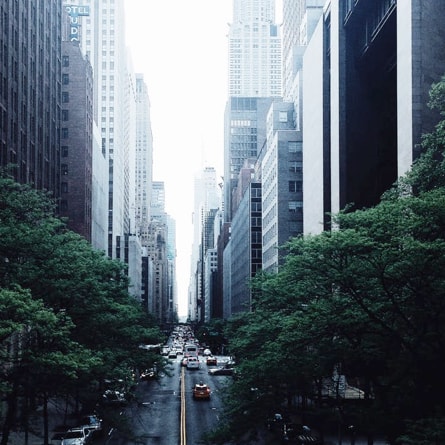 An overhead street view of a city block between a row of skyscrapers.